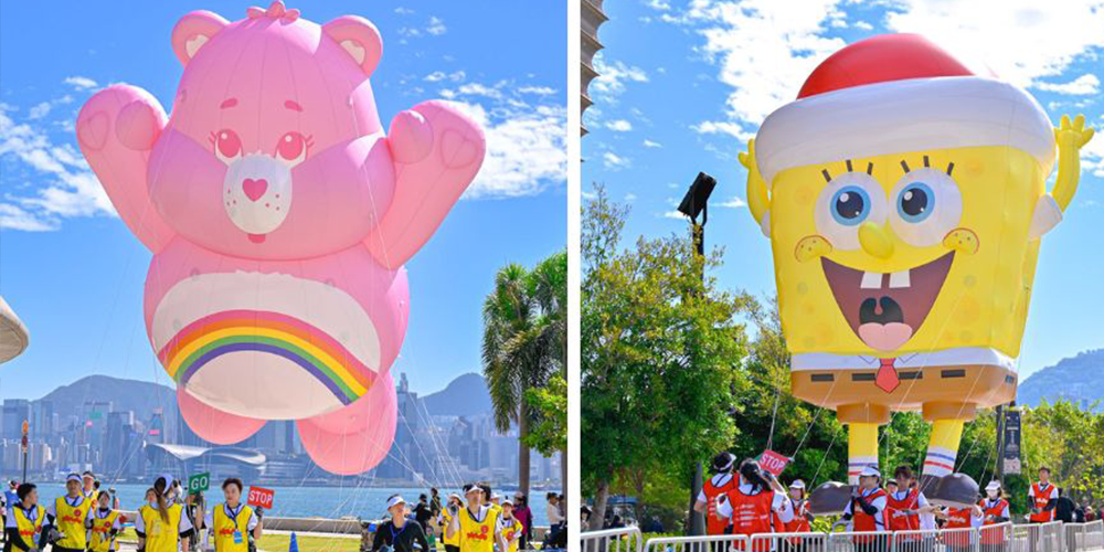 Huge pink bear balloon and yellow square character balloon floating above a street parade in Hong Kong's First Giant Christmas Balloon parade